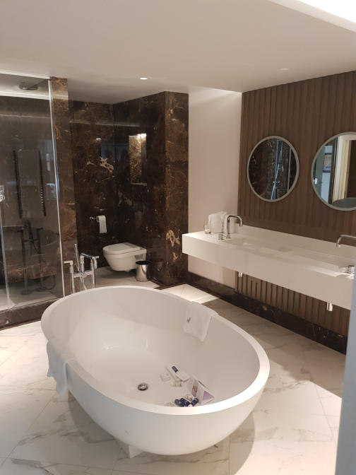 Hotel suite bathroom with free standing bath, steam room and marble tiles. Gessi taps